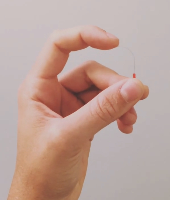 A fine, flexible acupuncture needle held between fingers